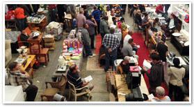 Busy auction floor with furniture and decor lots